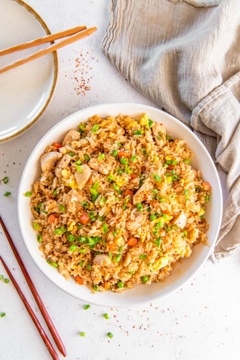 chicken fried rice in a white bowl with chopsticks.