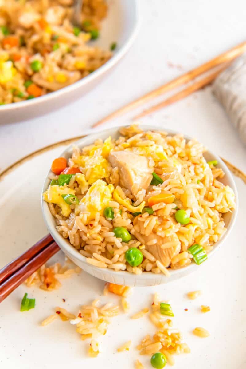 chicken fried rice in a white bowl with chopsticks.