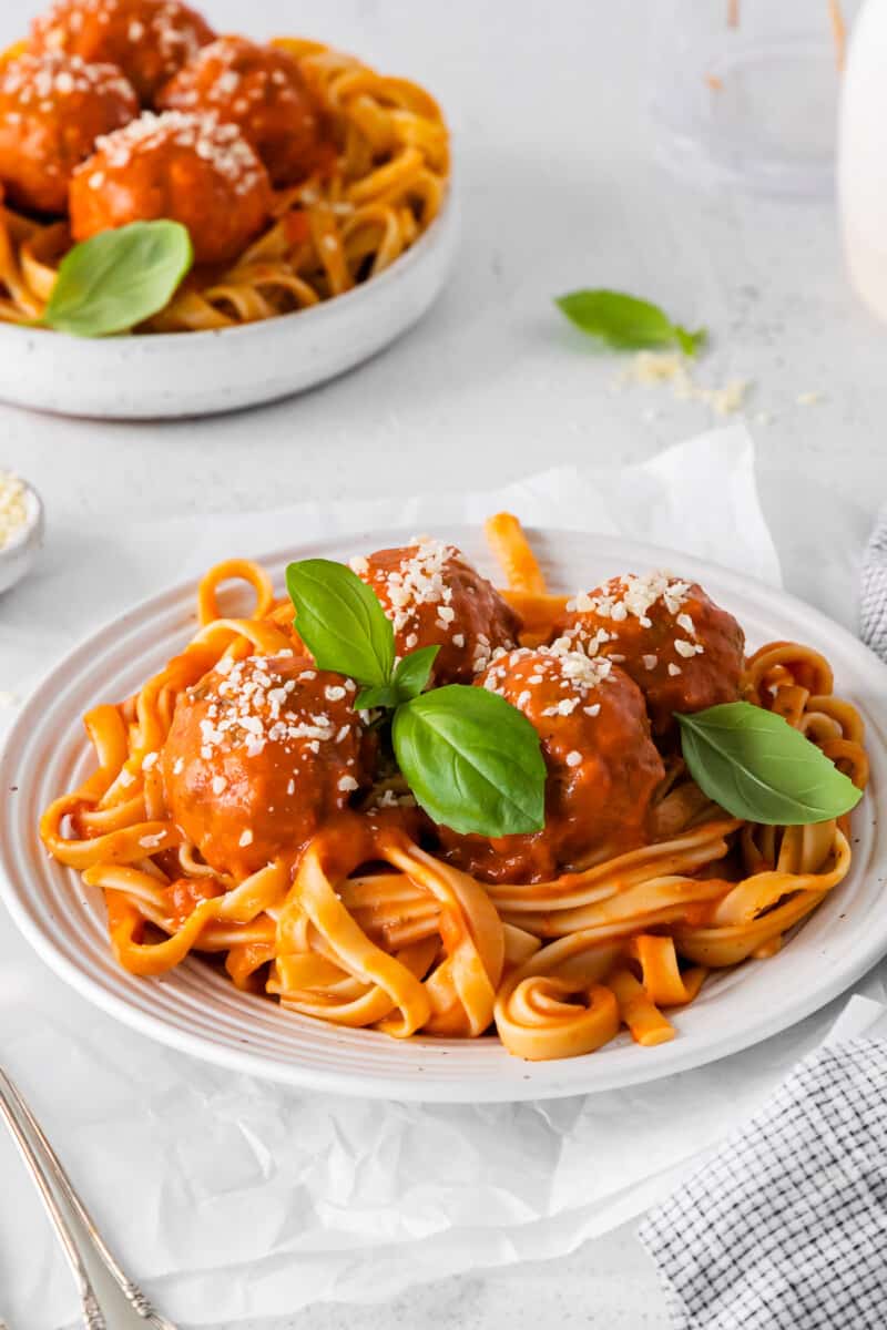 almôndegas de frango parmesão sobre espaguete em uma tigela branca.