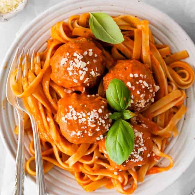 overhead view of chicken parmesan meatballs in a white bowl with a fork and spoon.