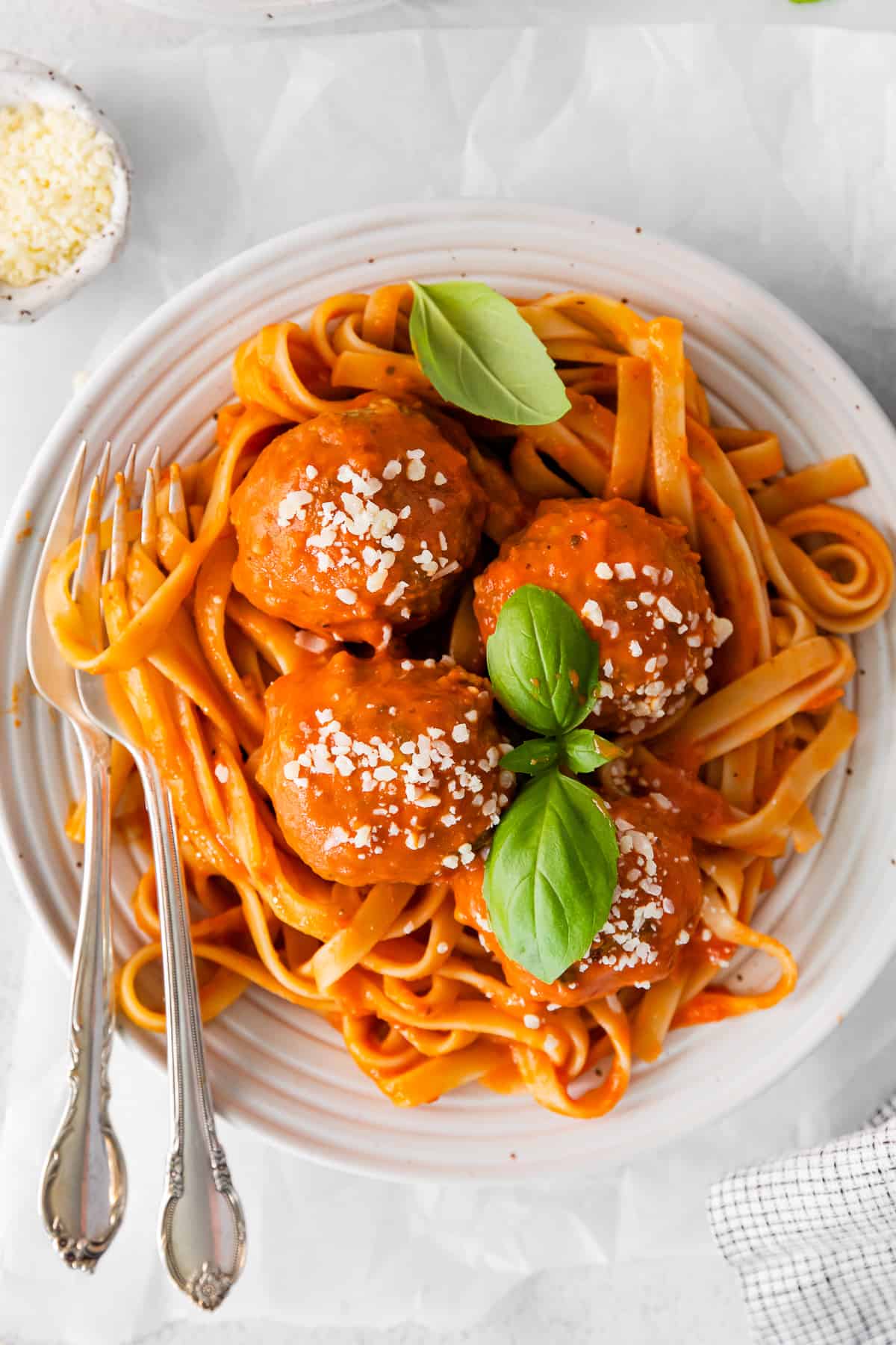 overhead view of chicken parmesan meatballs in a white bowl with 2 forks.