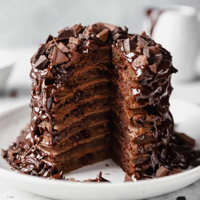 A delectable stack of chocolate pancakes, warm and fluffy, is delicately placed on a pristine plate.