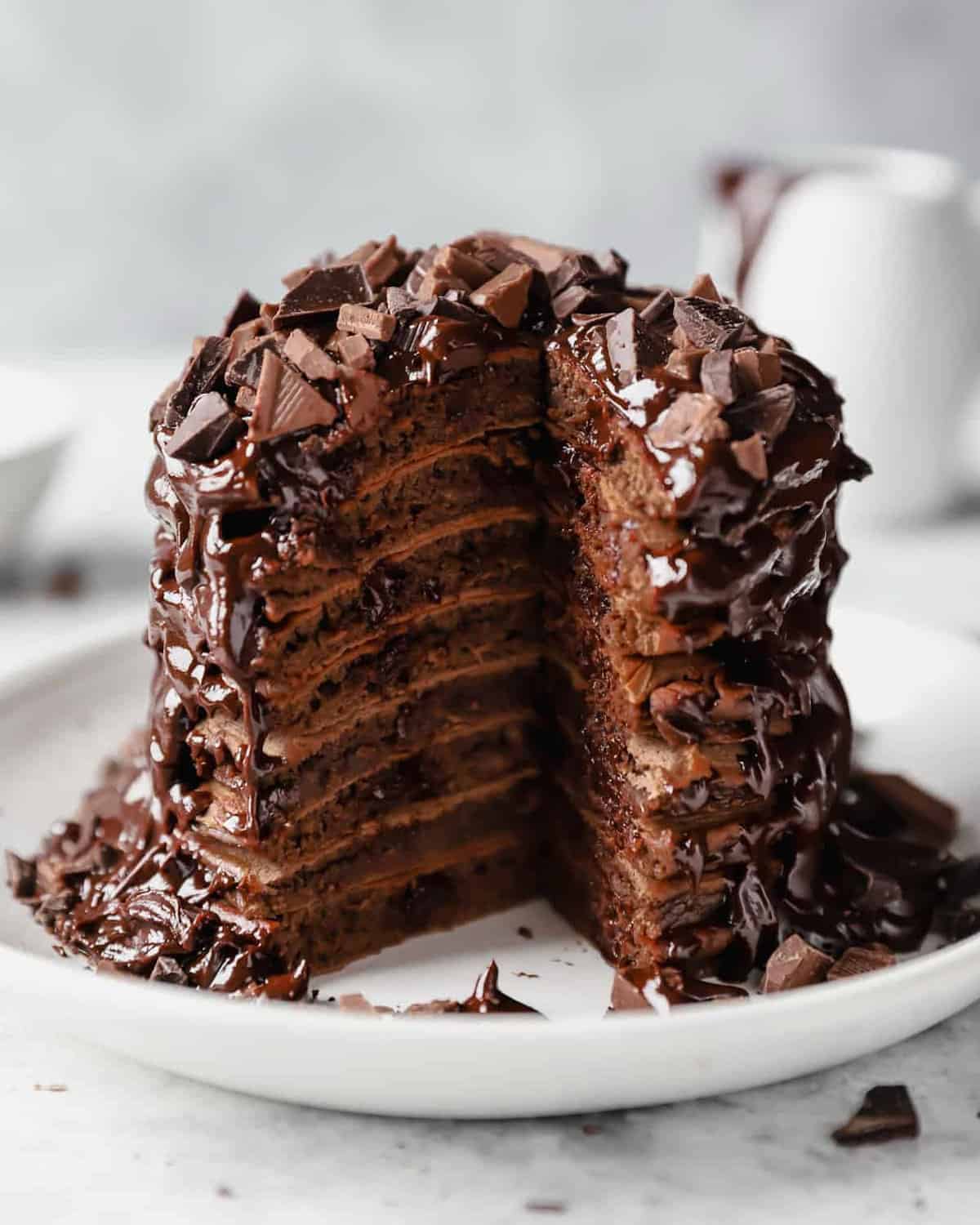 A delectable stack of chocolate pancakes, warm and fluffy, is delicately placed on a pristine plate.