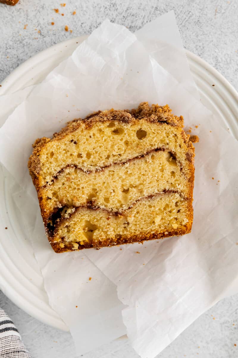 a slice of cinnamon roll bread on parchment paper on a white plate.