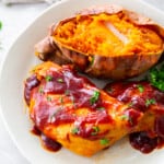 crockpot bbq chicken with sweet potato and parsley on a white plate.