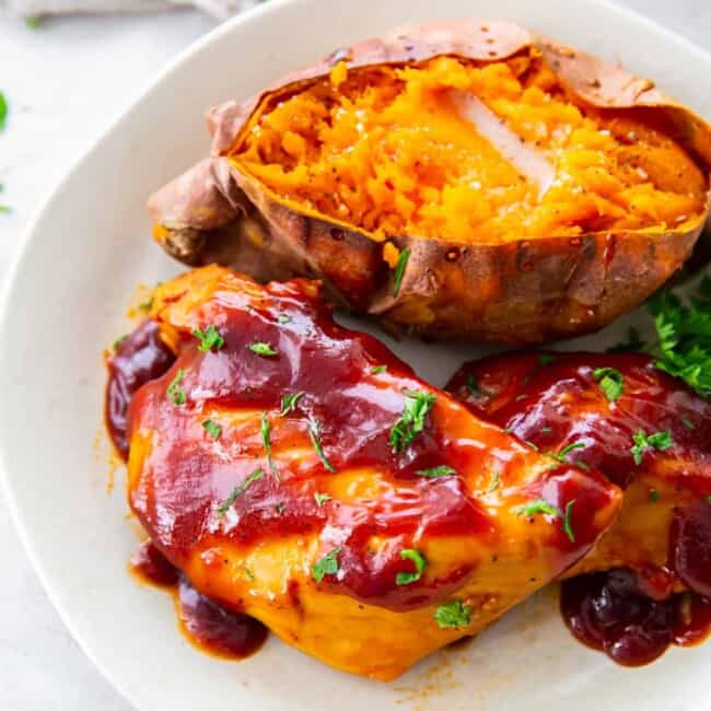 crockpot bbq chicken with sweet potato and parsley on a white plate.