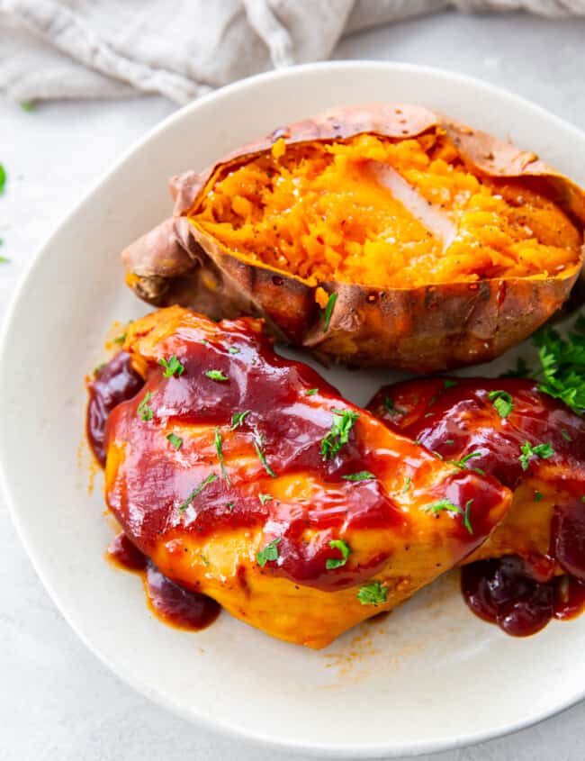 crockpot bbq chicken with sweet potato and parsley on a white plate.