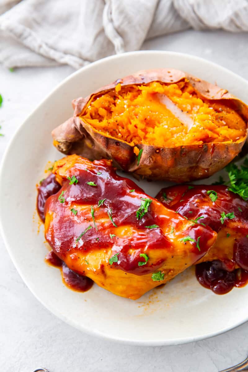crockpot bbq chicken with sweet potato and parsley on a white plate.
