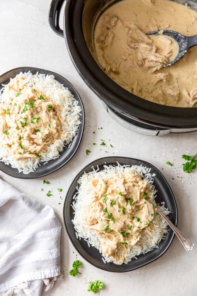 servings of crockpot chicken and gravy on black plates.