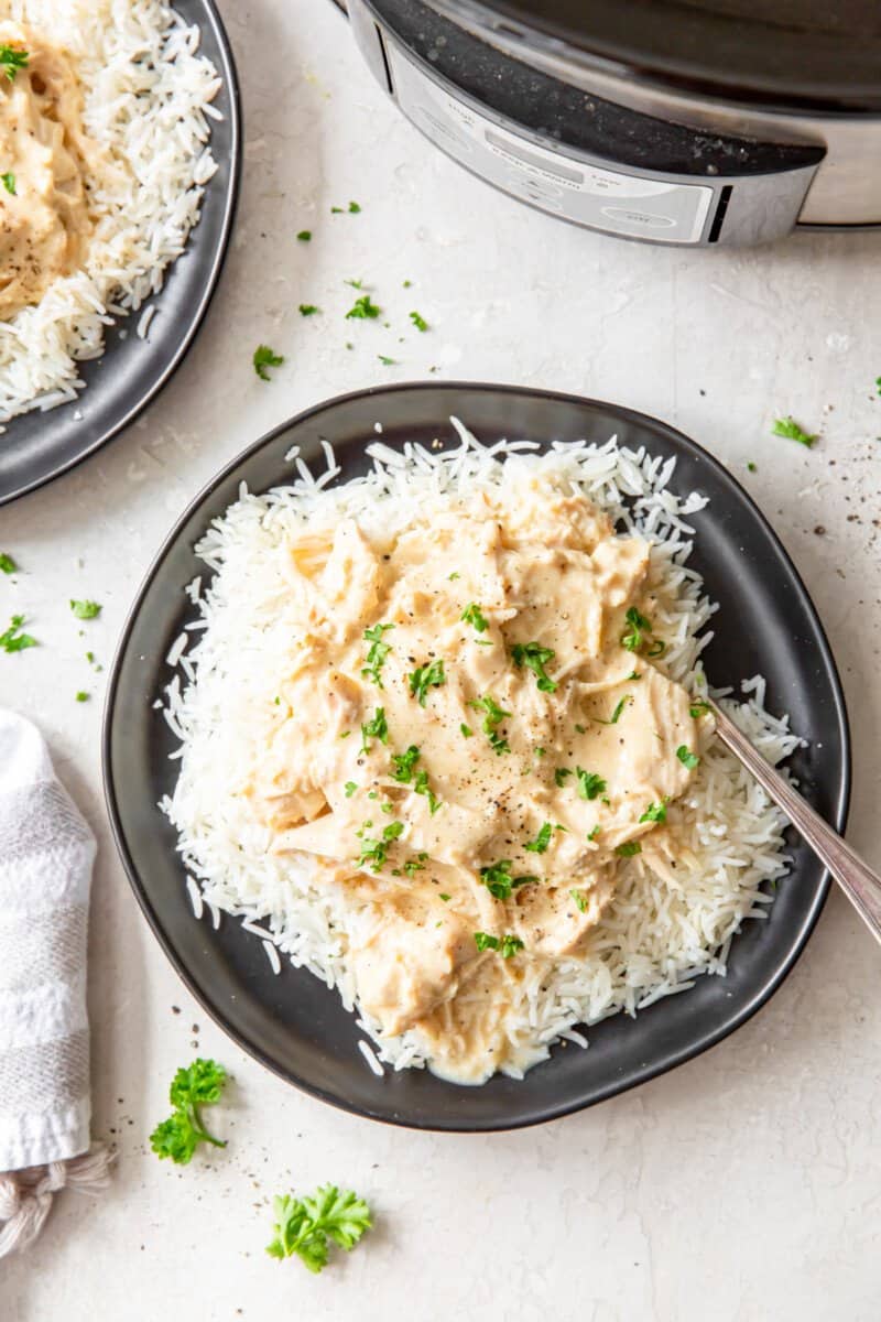 overhead view of a serving of crockpot chicken and gravy on a black plate.