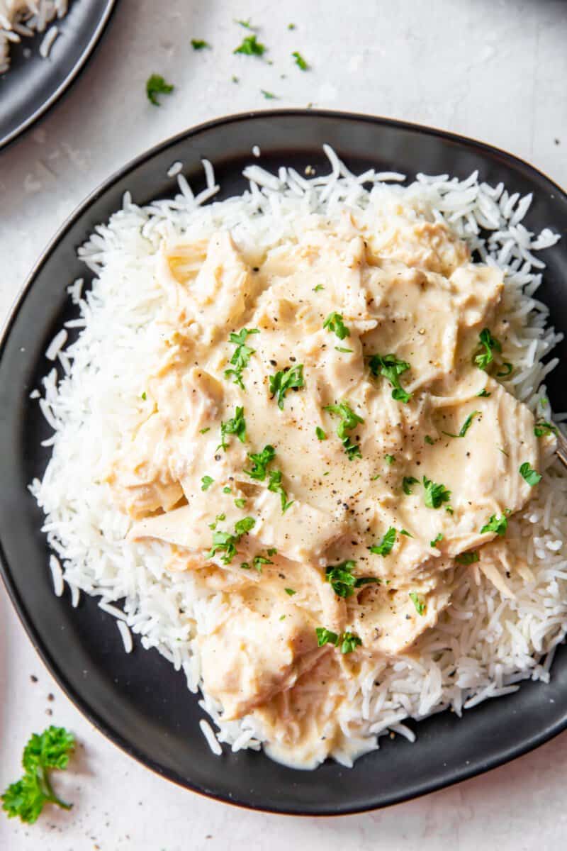 close up of crockpot chicken and gravy on a black plate.