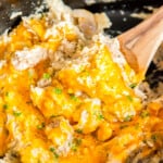 close up of crockpot chicken and rice on a wooden spoon.