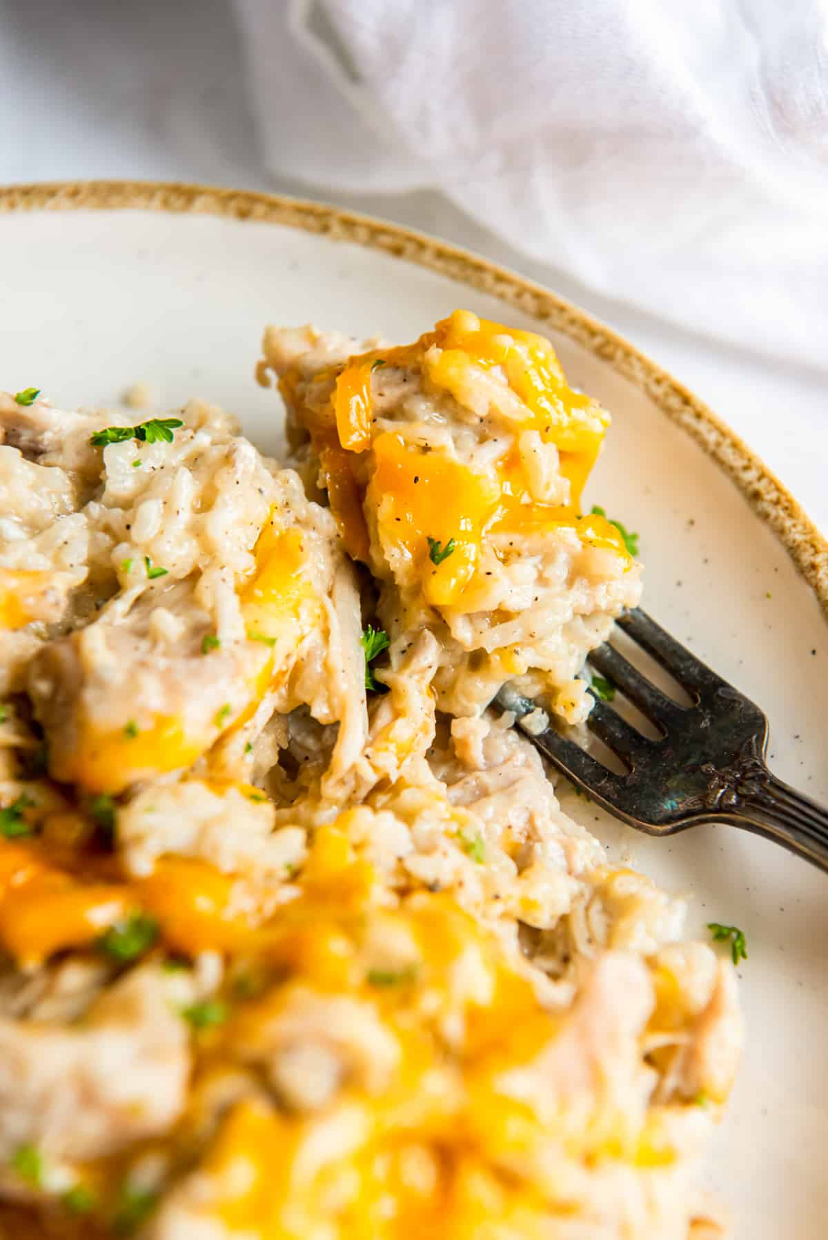 närbild av ccrockpot kyckling och ris på en vit platta med en gaffel.
