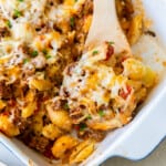 hamburger casserole in a white baking dish with a wood serving spoon