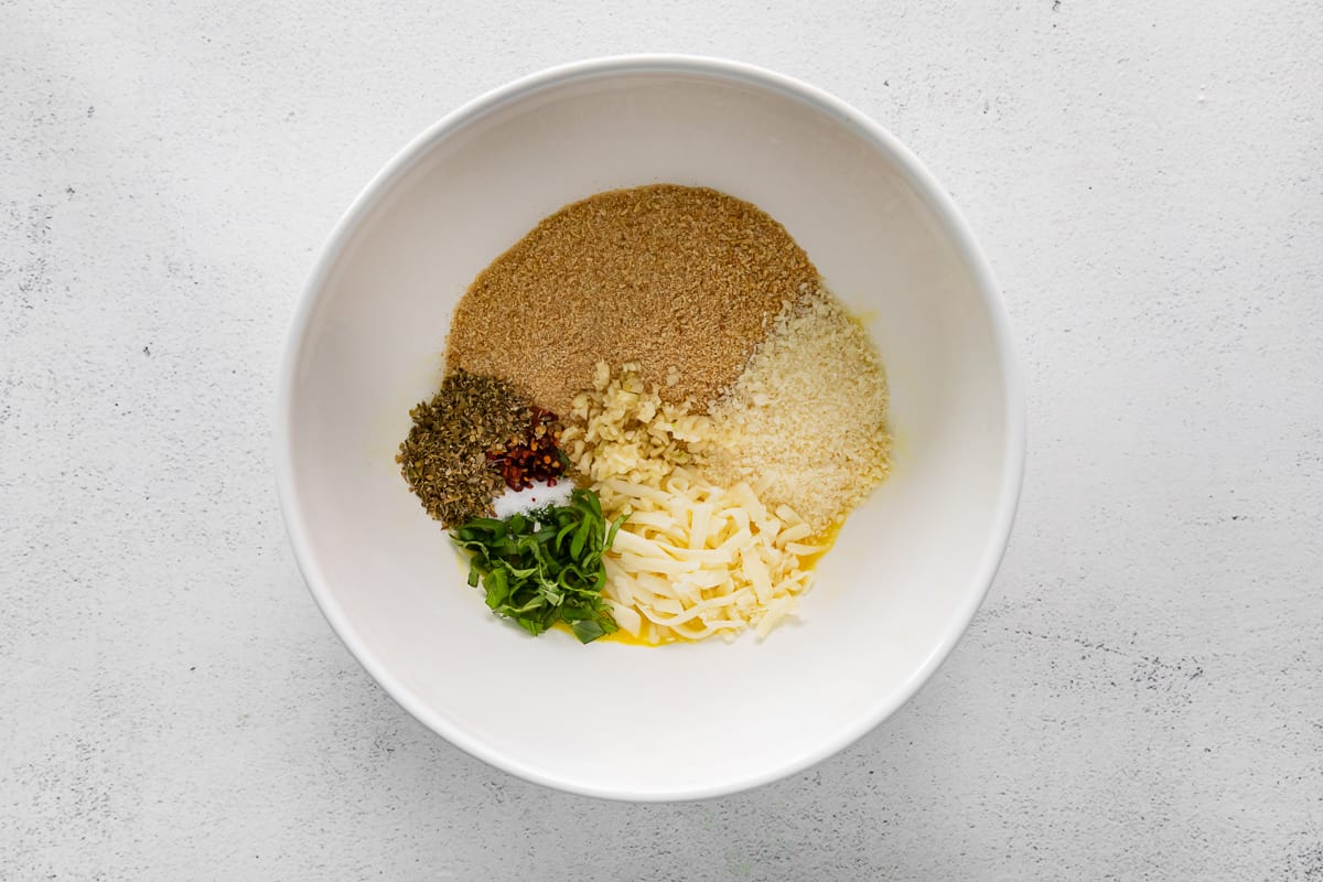 Breadcrumb mixture for chicken Parmesan meatballs in a white bowl.
