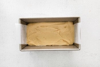 overhead view of cinnamon roll bread batter in a parchment lined loaf pan.