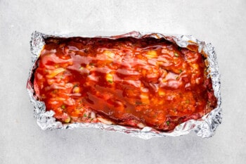 shaped instant pot meatloaf wrapped in aluminum foil and coated in glaze.