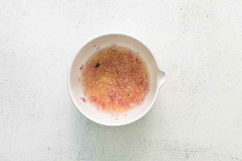 overhead view of lemon juice shallot and garlic in a white bowl.