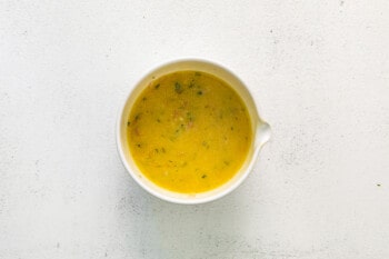 overhead view of lemon vinaigrette for mediterranean orzo salad in a white bowl.