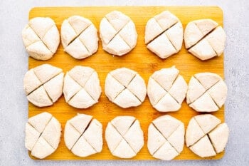 biscuit dough rounds cut into quarters on a wooden cutting board.