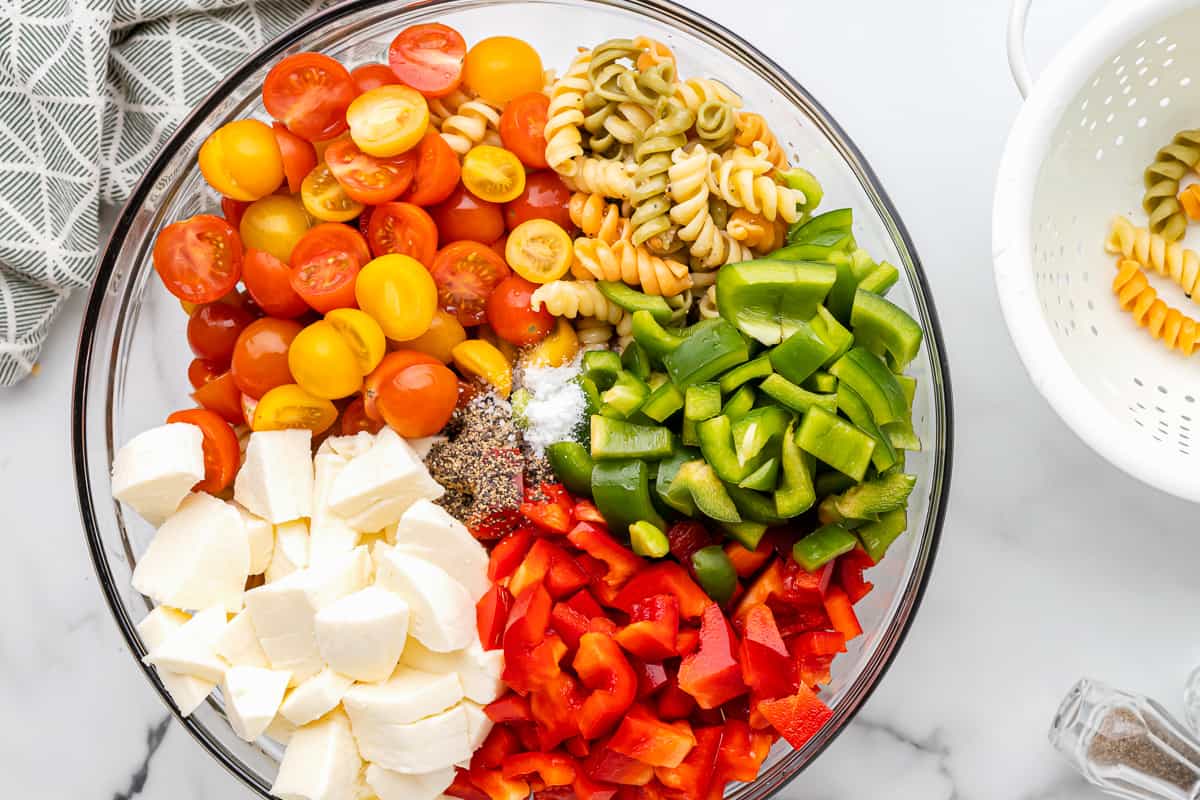 tricolor pasta salad ingredients in a glass bowl.
