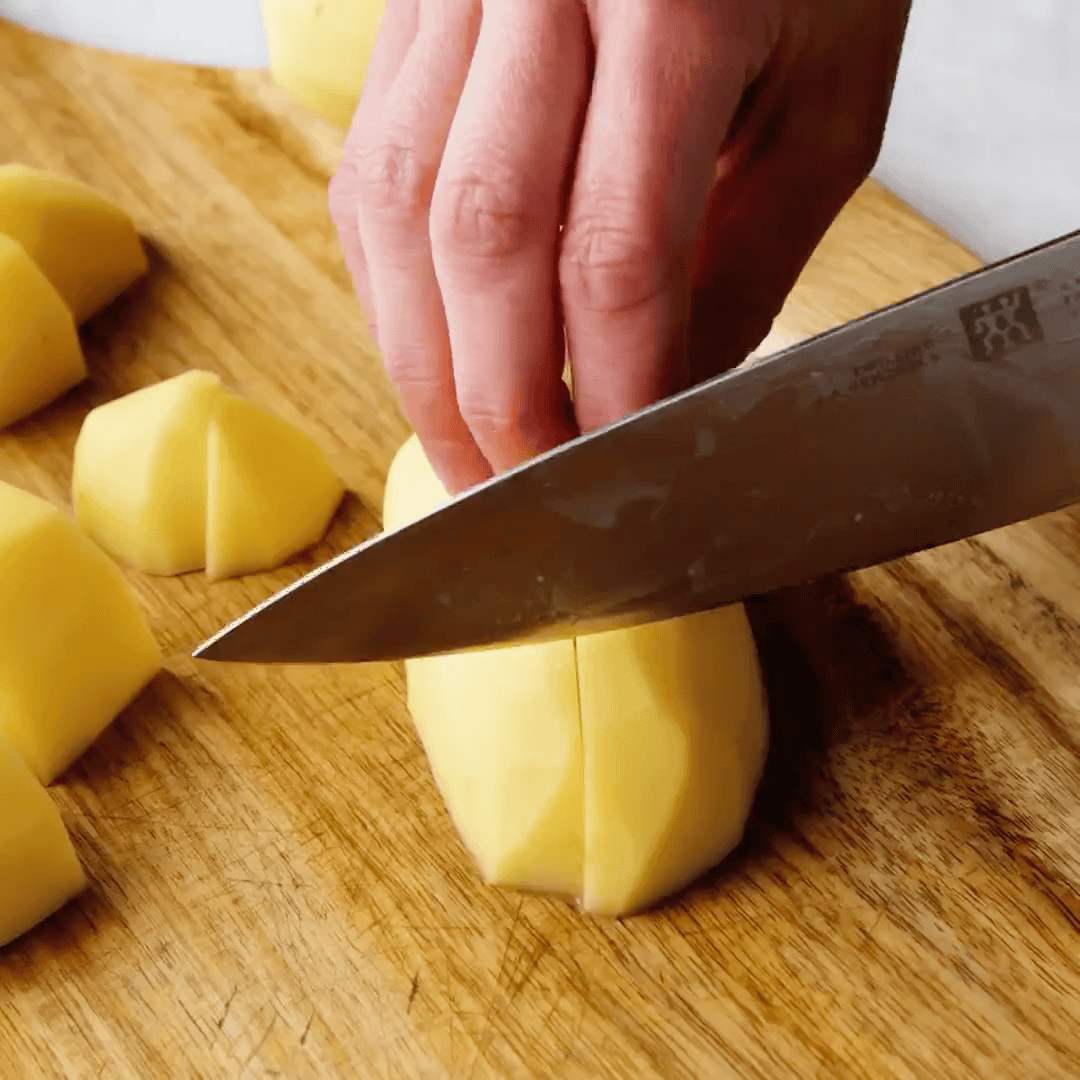 Cutting potatoes with a knife on a cutting board.