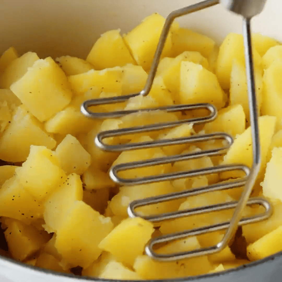 Mashing the cooked potatoes.