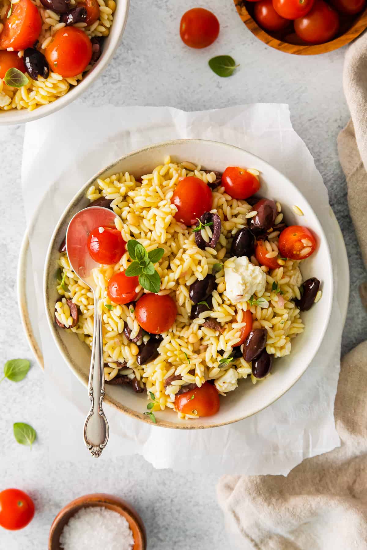 mediterranean orzo salad in a white bowl with a spoon.