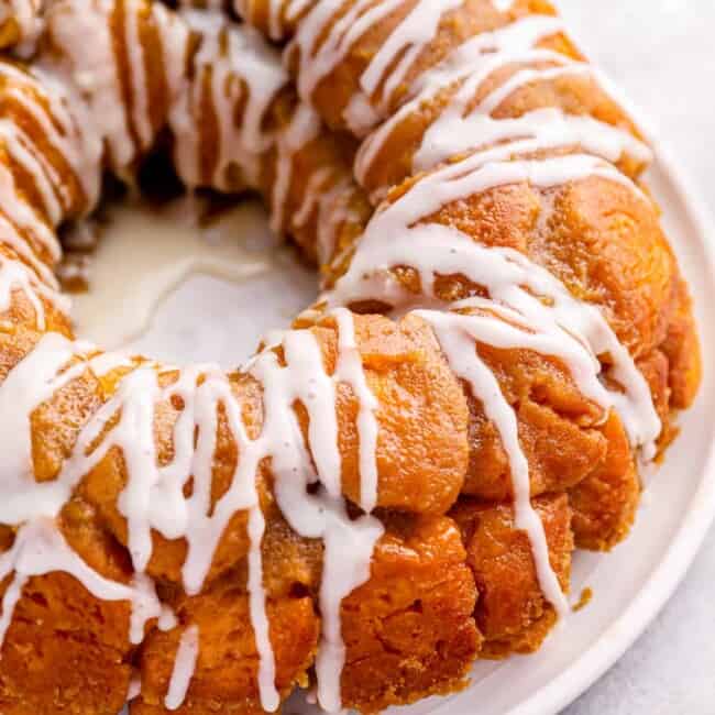 close up of iced easy monkey bread on a white serving plate.