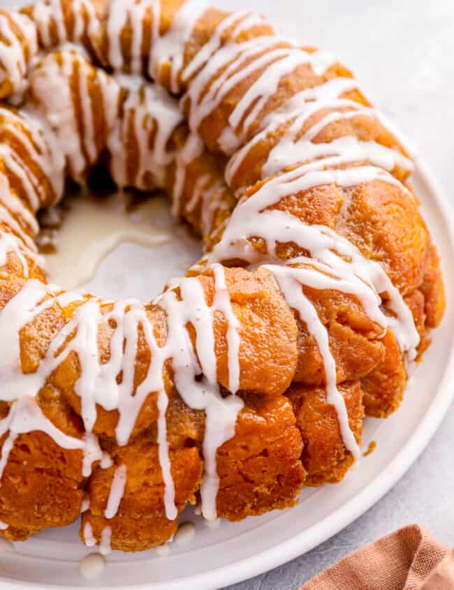 close up of iced easy monkey bread on a white serving plate.