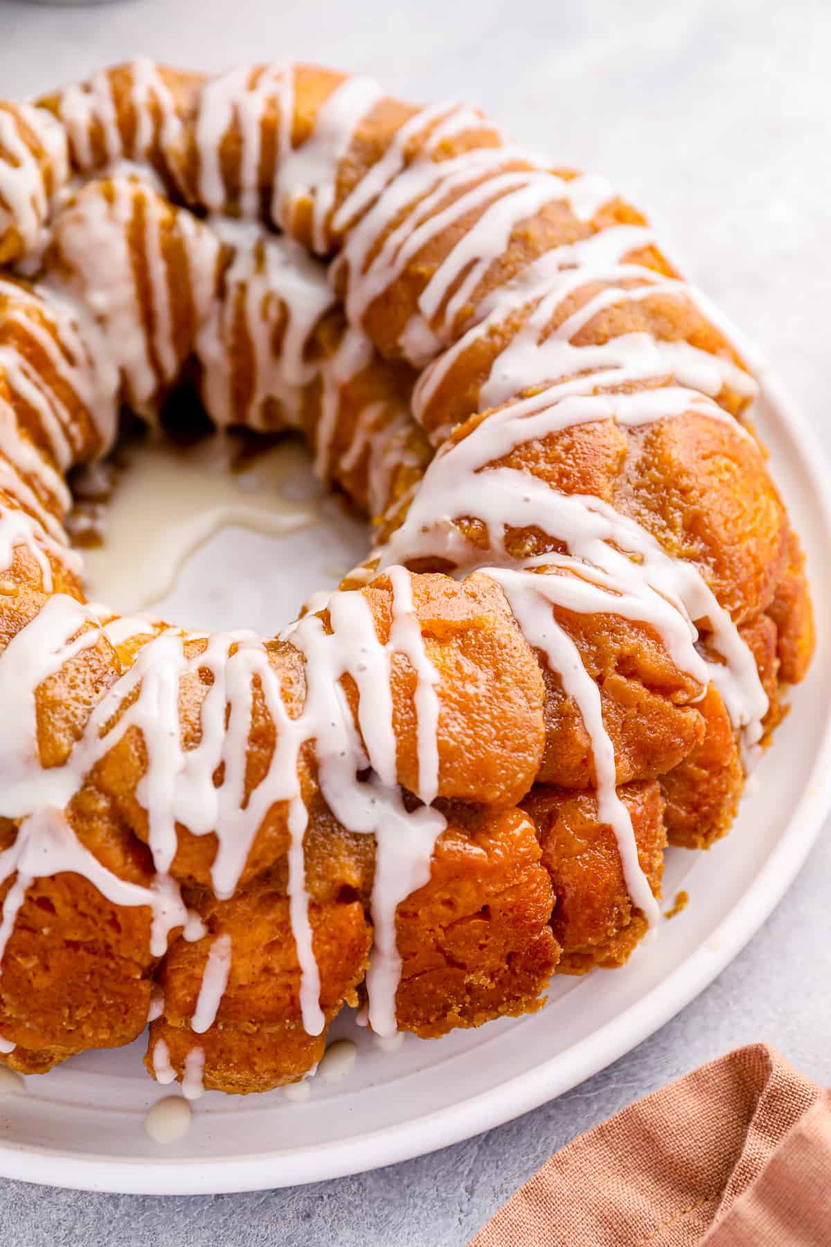 close up of iced easy monkey bread on a white serving plate.
