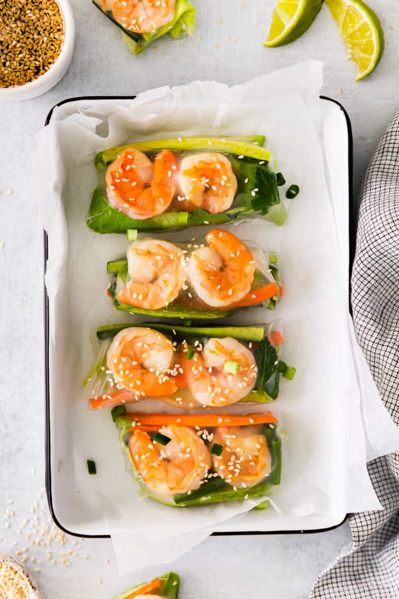 4 shrimp summer rolls in a white rectangular tray.