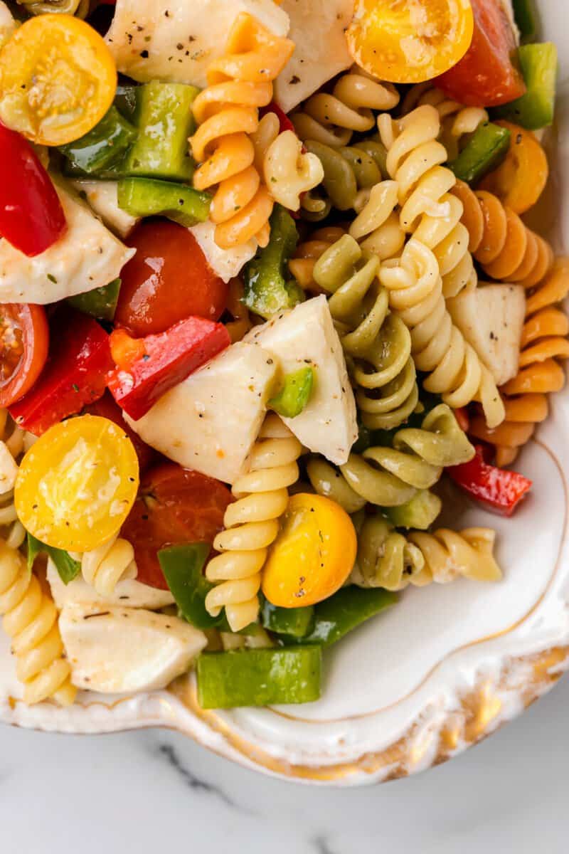 close up of tricolor pasta salad in a white bowl.