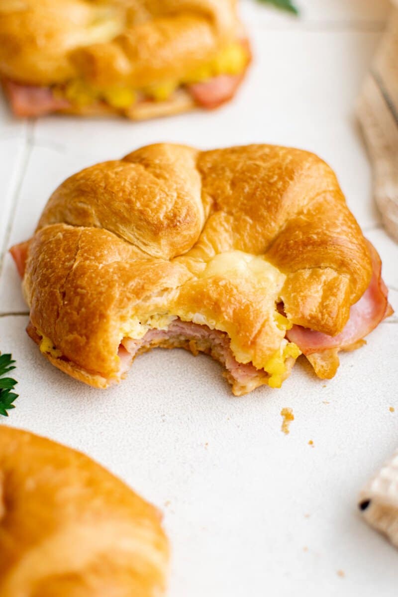 bitten croissant breakfast sandwich on a table.