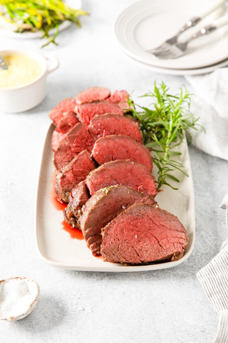 sliced crockpot beef tenderloin on a white plate.