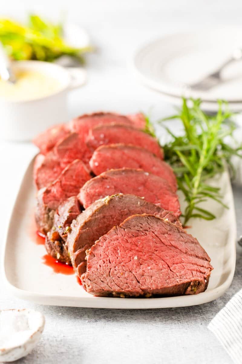 sliced crockpot beef tenderloin on a white plate.