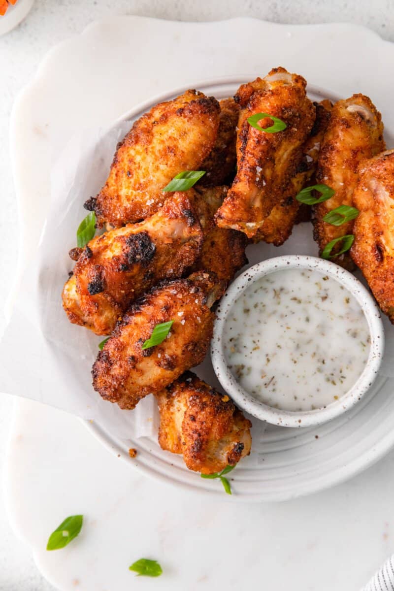 dry rub chicken wings on a white plate with dipping sauce.
