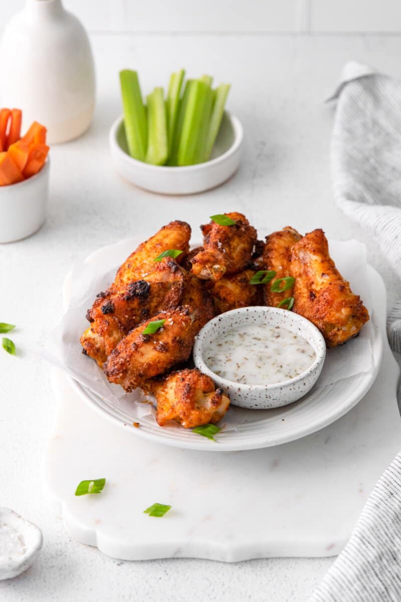 dry rub chicken wings on a white plate with dipping sauce.