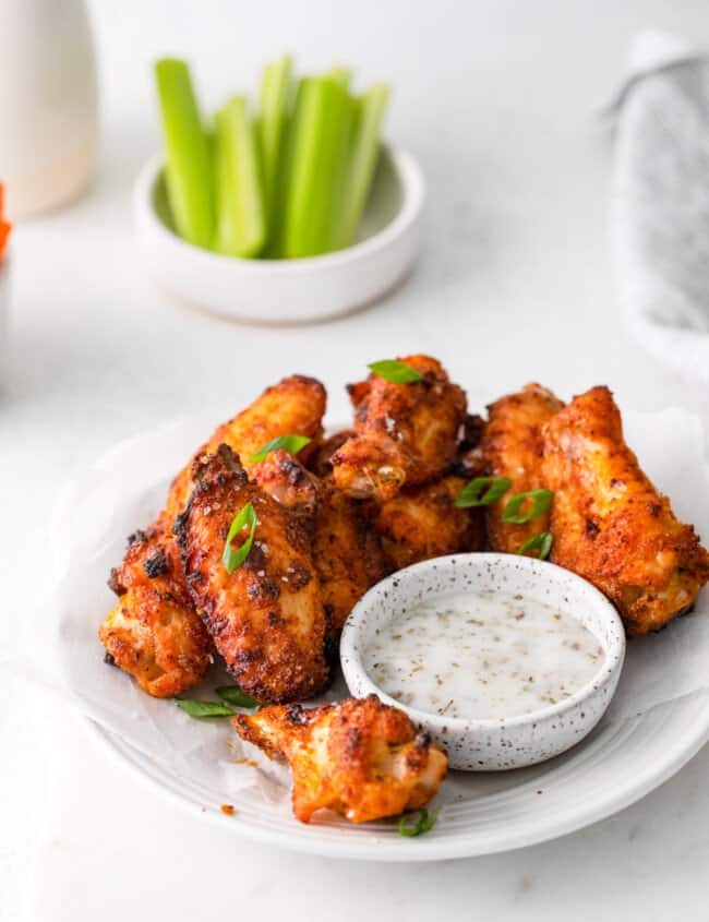 dry rub chicken wings on a white plate with dipping sauce.
