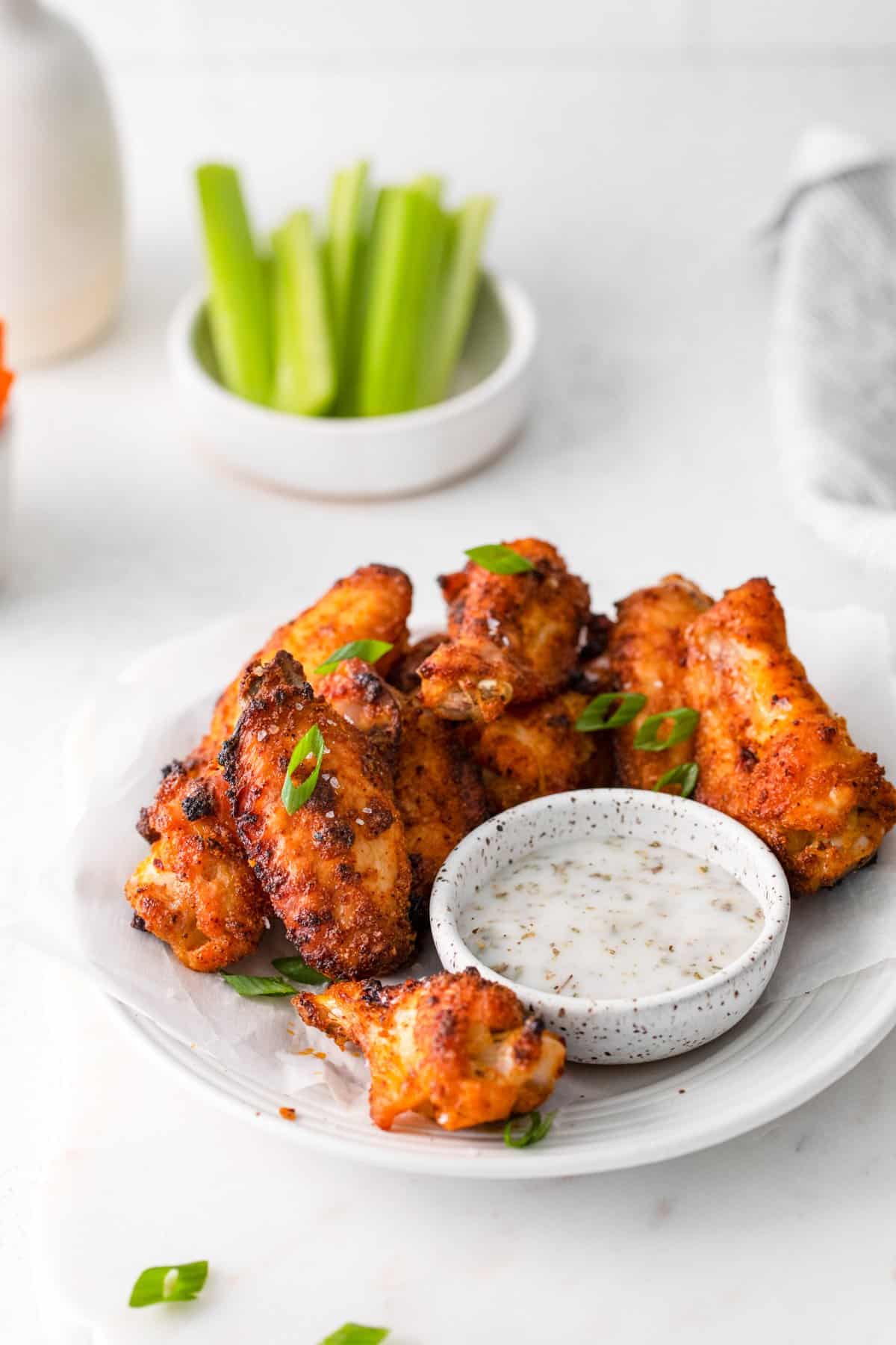 dry rub chicken wings on a white plate with dipping sauce.
