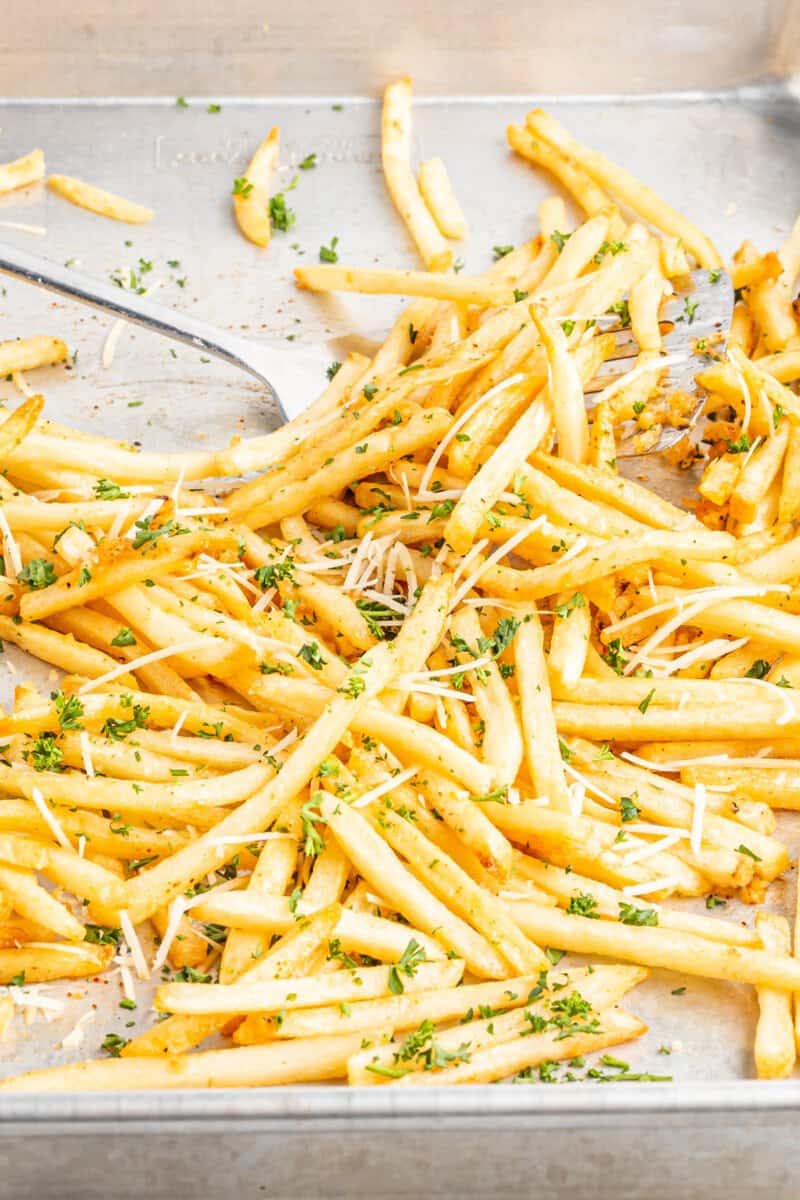 garlic parmesan fries on a sheet pan with a spatula.