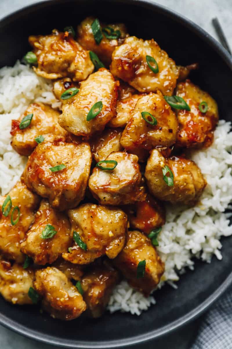 honey chicken over white rice in a black bowl.