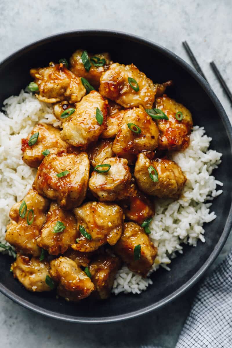 honey chicken over white rice in a black bowl.