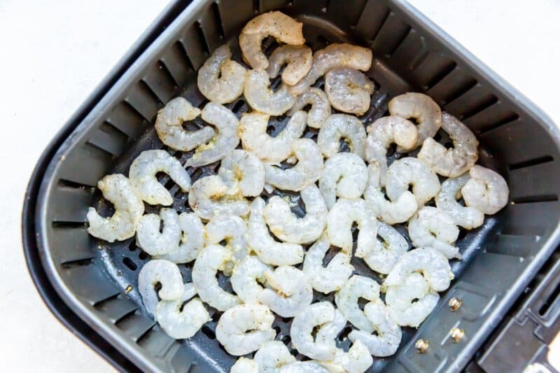 raw shrimp in an air fryer basket.