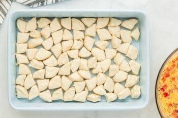 Shredded chicken in a baking dish served alongside biscuit breakfast casserole.