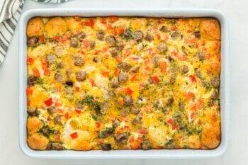 parsley garlic butter brushed over biscuit breakfast casserole in a baking pan.