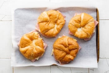 4 croissant breakfast sandwiches on a baking sheet.
