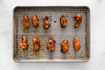 baked dry rubbed chicken wings on a wire rack set in a baking sheet.