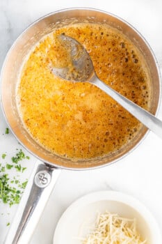 garlic parmesan butter in a saucepan with a spoon.