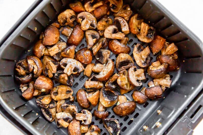 cooked sliced mushrooms in an air fryer basket.